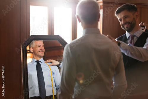 Fotografía Tailor fitting businessman at mirror in menswear shop