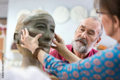 Woman sculpting clay face in pottery studio