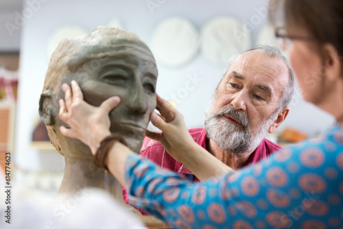 Canvas Print Woman sculpting clay face in pottery studio