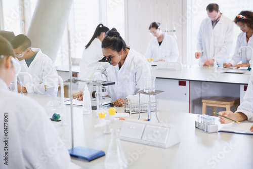 College students using microscope conducting scientific experiment in laboratory