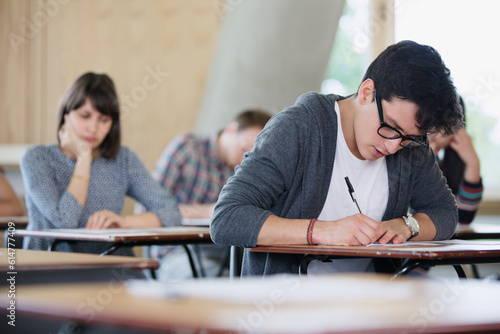 Focused male college student taking test at desk in classroom photo
