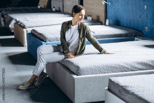 Woman lying on bed with orthopedic pillow in furniture store