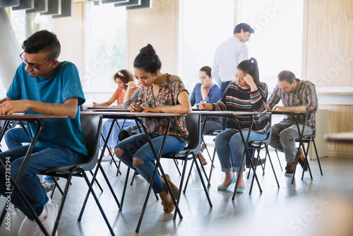 Professor watching college students taking test in classroom photo