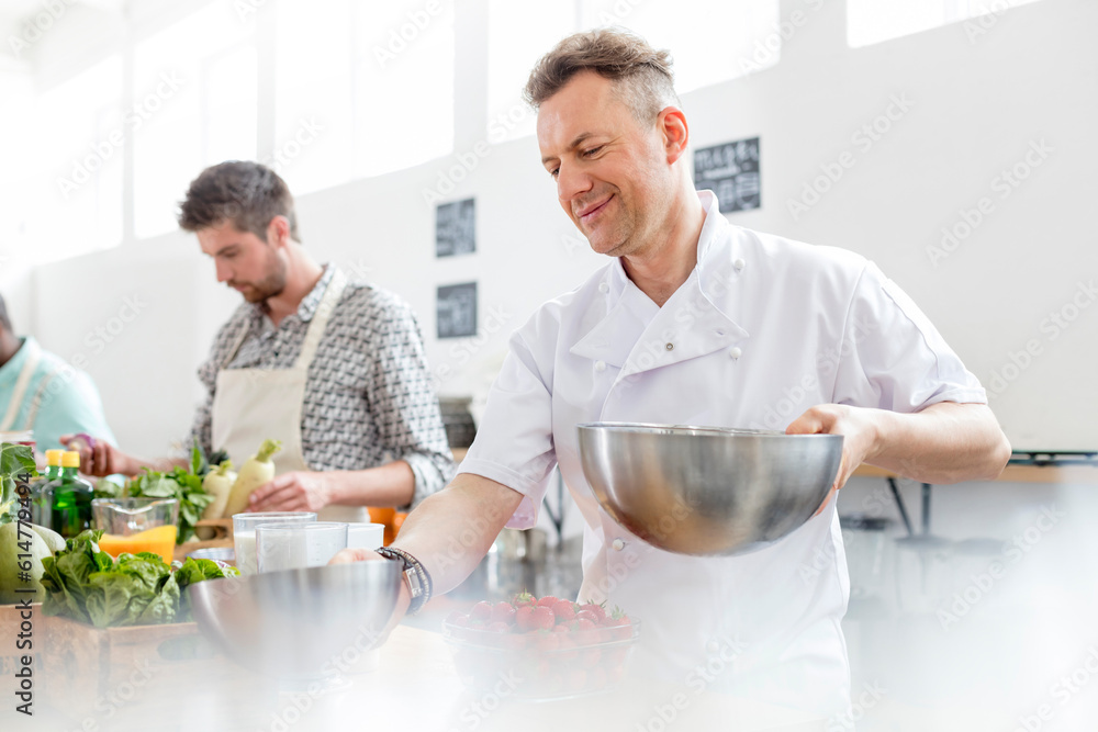 Chef teacher holding bowls in cooking class kitchen Chef teacher holding bowls in cooking class kitchen