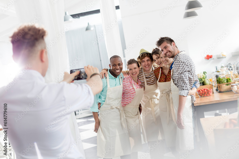 Naklejka premium Chef teacher photographing students camera phone in cooking class kitchen