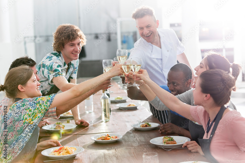 Chef teacher students toasting wine glasses in cooking class kitchen Chef teacher students toasting wine glasses in cooking class kitchen