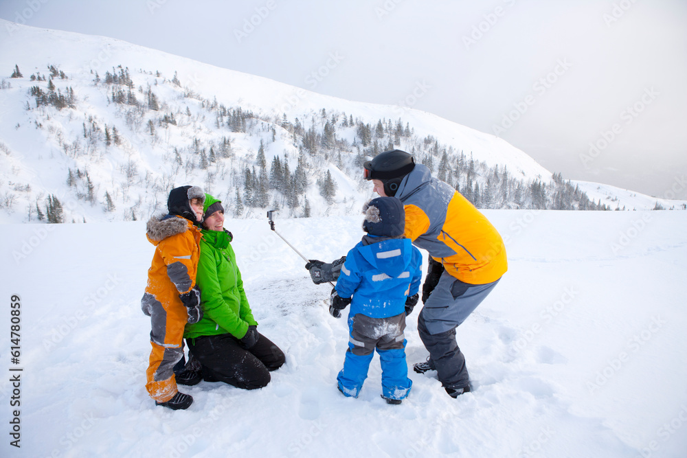 Family using selfie stick on snowy mountain