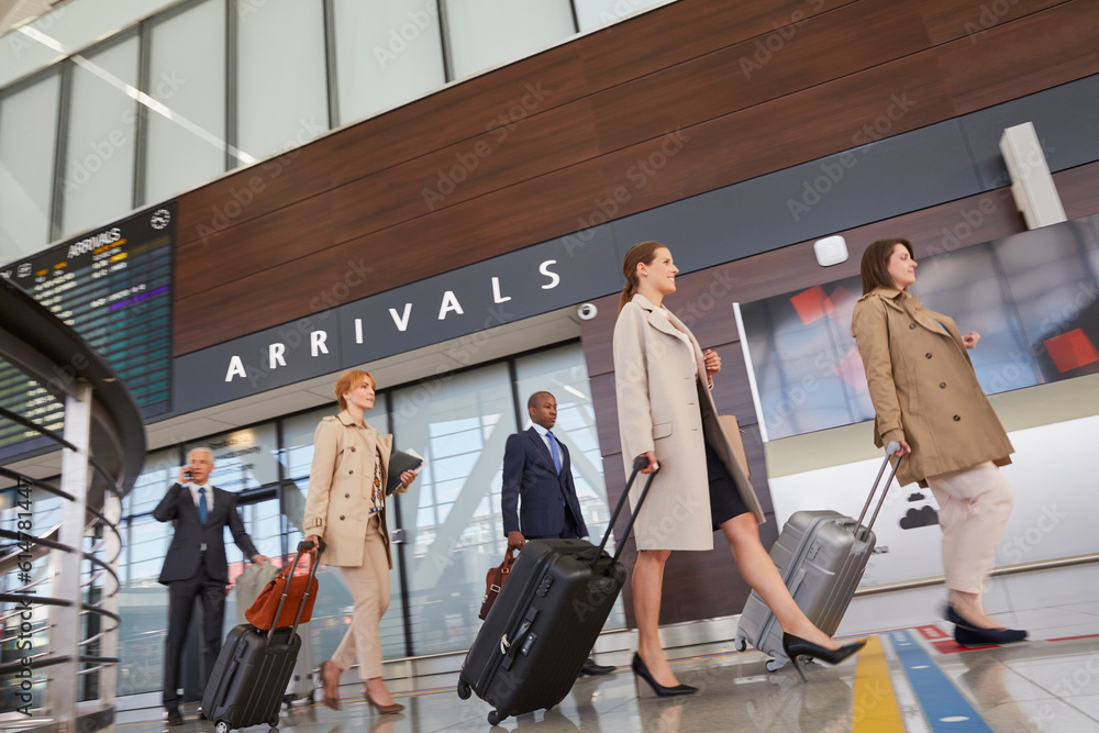 Φωτογραφία Business people walking pulling suitcases in airport concourse