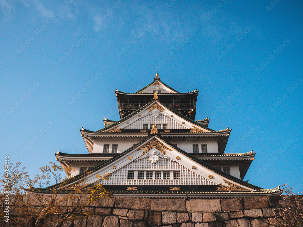 Majestic Osaka Castle stands tall, surrounded by vibrant cherry blossoms. Its elegant architecture reflects centuries of Japanese history and culture. Osaka Castle, a grand symbol of Japan