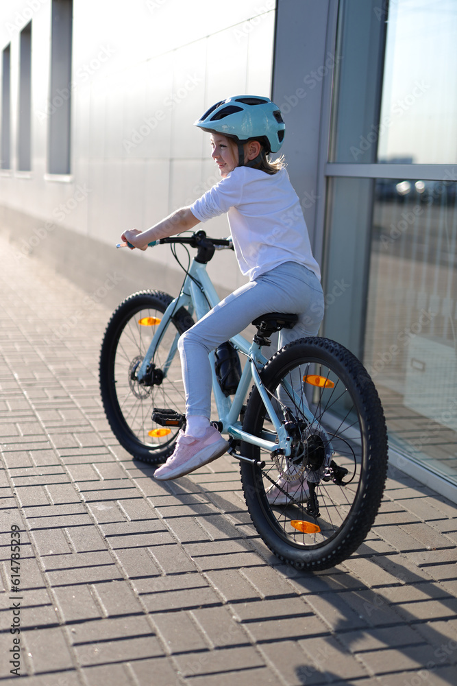 Little girl child in a helmet on a bicycle view from the back.