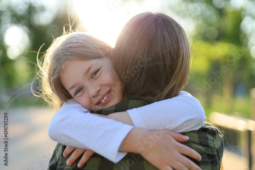 Canvastavla Portrait of a cute girl who hugs her mother in the rays of sunset in the park