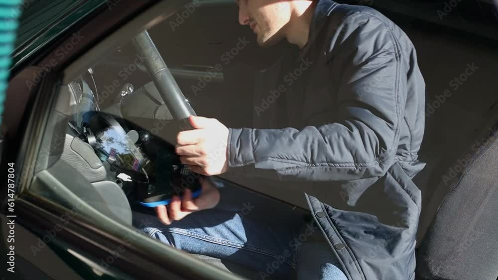 A young man wipes the dust in the interior of a car. A young man wipes the dust in the interior of a car.