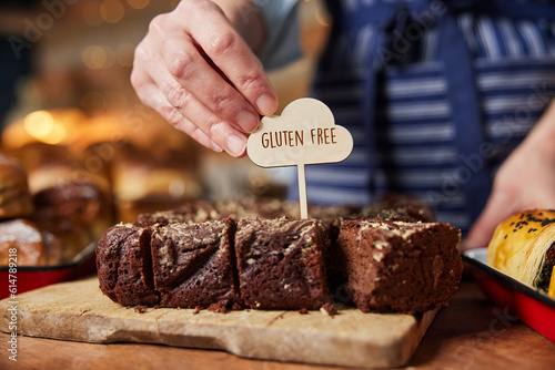 Sales Assistant In Bakery Putting Gluten Free Label Into Freshly Baked Brownies