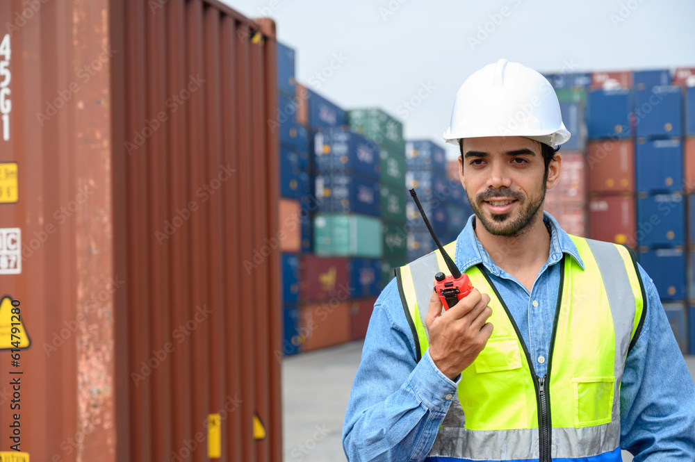 handsome caucasian foreman or engineer man with white helmet and reflection shirt using walkie talkie for control labor in front of container cargo store. import and export logistic industry concept. handsome caucasian foreman or engineer man with white helmet and reflection shirt using walkie talkie for control labor in front of container cargo store. import and export logistic industry concept.