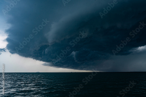 View of tropical ocean storm with menacing clouds and rain showering below, Light in the dark and dramatic storm clouds background
