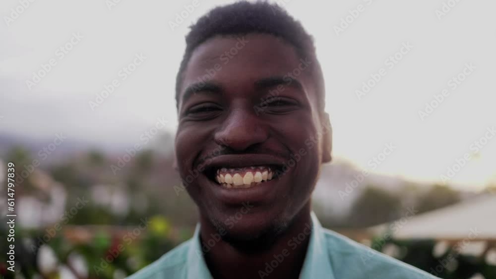 Authentic African young man smiling at camera with sunset background Authentic African young man smiling at camera with sunset background