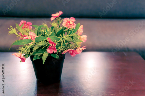 A flower vase set on a wooden table has a soft blurred