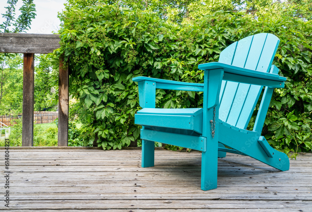 empty Adirondack chair on a wooden backyard deck, summer scenery with a green vine empty Adirondack chair on a wooden backyard deck, summer scenery with a green vine