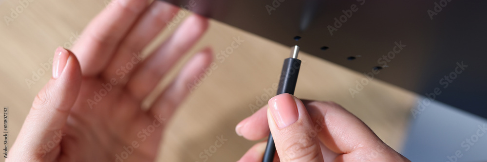 Person hand connects a black USB-C or Type C power cable to computer Person hand connects a black USB-C or Type C power cable to computer