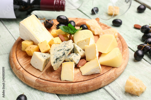 Board with pieces of tasty cheese on light wooden background