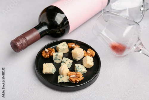 Pieces of tasty cheese, glasses and bottle with wine on light background