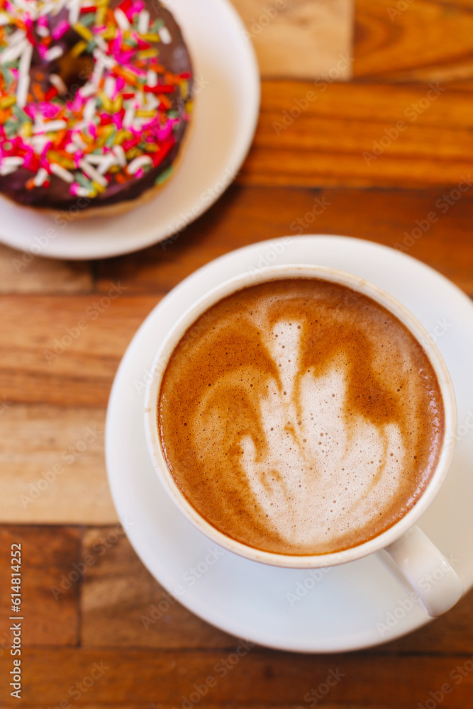 Cappuccino and donut on a wooden background, top view. Sweet dessert with coffee Cappuccino and donut on a wooden background, top view. Sweet dessert with coffee