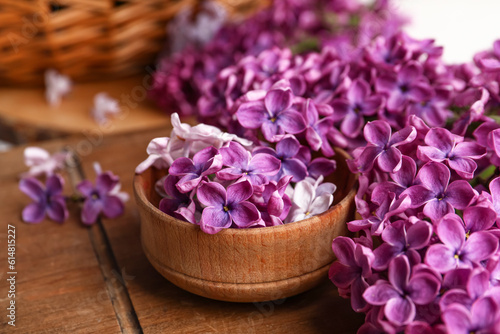 Bowl of beautiful fragrant lilac flowers on wooden table