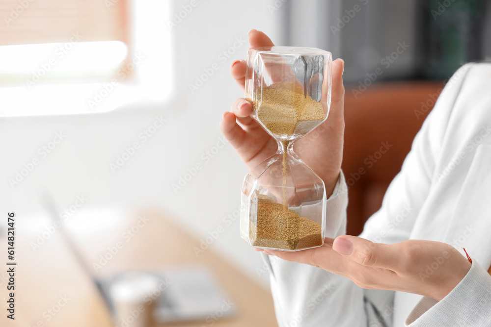 Young businesswoman with hourglass in office, closeup Young businesswoman with hourglass in office, closeup