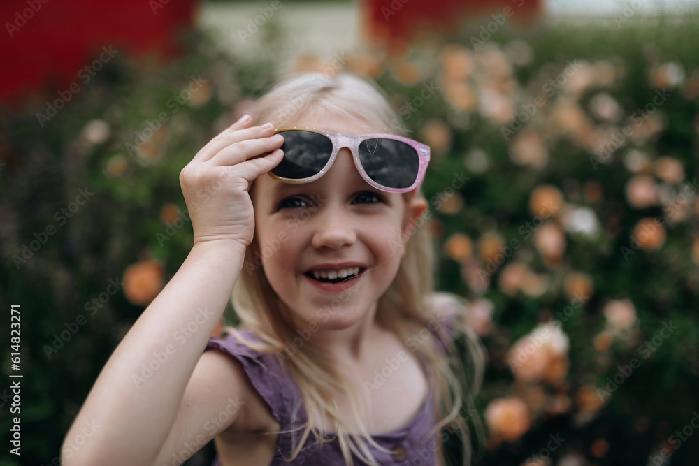 a charismatic girl in trendy sunglasses on a background of flowers a charismatic girl in trendy sunglasses on a background of flowers