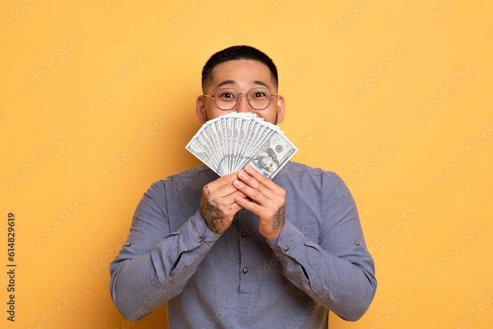 Big Profit. Excited Young Asian Guy Holding Dollar Cash Fan Near Face Big Profit. Excited Young Asian Guy Holding Dollar Cash Fan Near Face