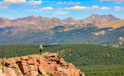 Hiker on top off Shrine Mountain near Colorado's Vail Pass, with a view of the Sawatch Range in the background photo
