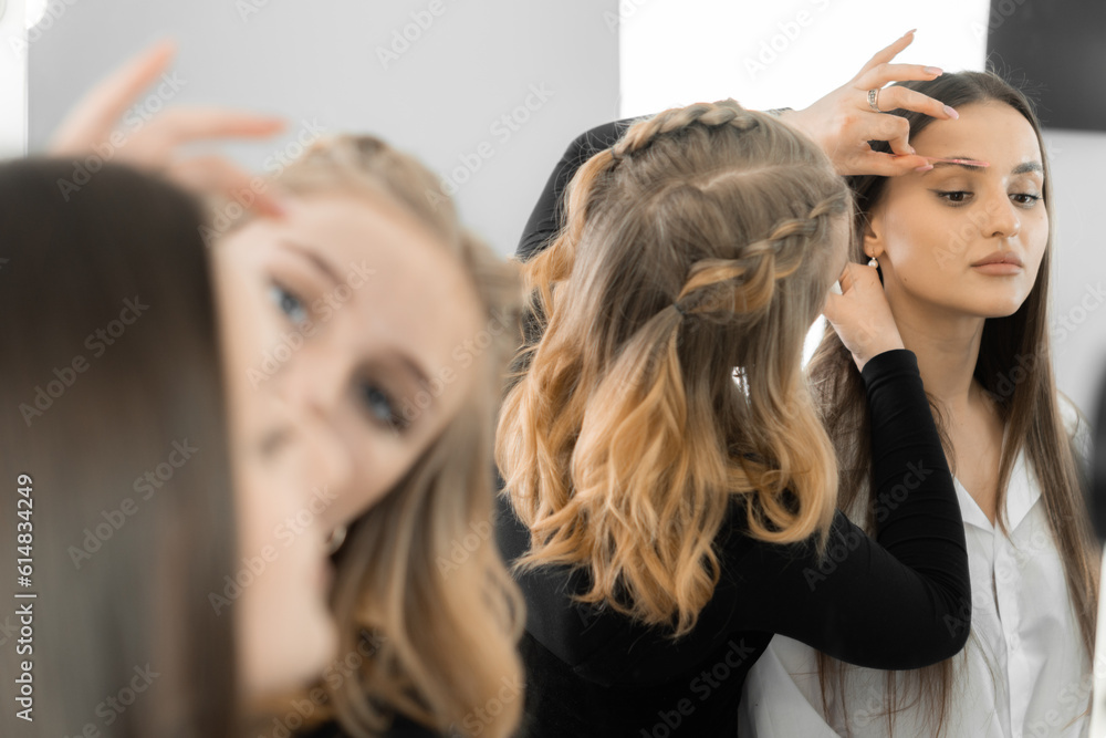 Fototapeta premium This photo conveys the atmosphere of a beauty salon, where the makeup artist improves the shape of the client's eyebrows. Each movement of the master is aimed at creating the perfect frame for the