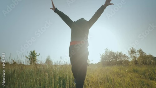 The child runs across the grass with his arms raised like an airplane.
