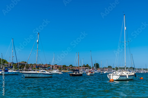 A view of sail boats moored close to the landing stage on the River Hamble, Hampshire in summertime
