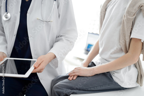 Doctor and child patient. The doctor is using tablet computer and is ready to examine the boy. The concept of ideal health in medicine