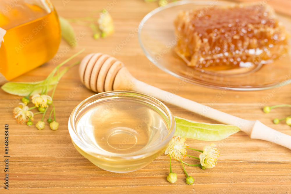 Linden honey with leaves and flowers on wooden table Linden honey with leaves and flowers on wooden table