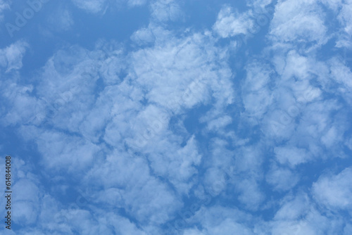 Blue sky with clouds. Spring or summer background.  White clouds on the blue sky have a complex pattern.  © achkin