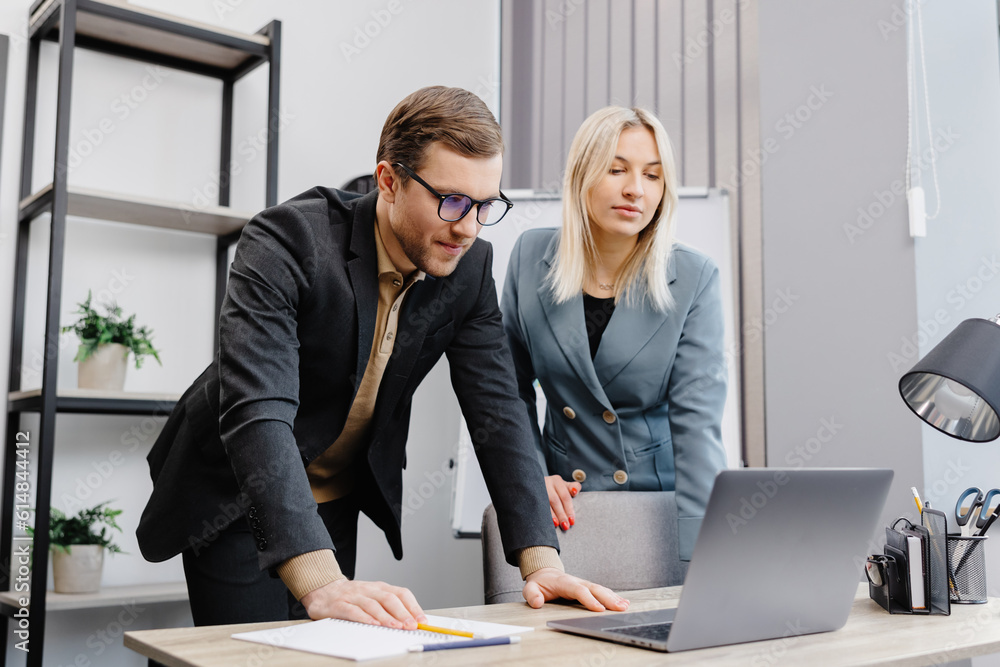Concentrated male businessman looking at computer monitor, working with a young female worker on a project, people holding a video meeting with a client or interviewing a job candidate. Concentrated male businessman looking at computer monitor, working with a young female worker on a project, people holding a video meeting with a client or interviewing a job candidate.
