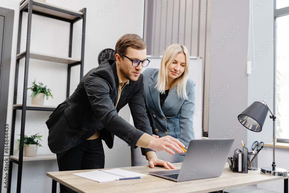 Concentrated male businessman looking at computer monitor, working with a young female worker on a project, people holding a video meeting with a client or interviewing a job candidate. Concentrated male businessman looking at computer monitor, working with a young female worker on a project, people holding a video meeting with a client or interviewing a job candidate.