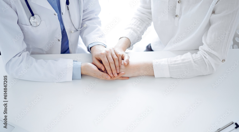 Doctor and patient sitting near each other at the table in clinic office. The focus is on female physician's hands reassuring woman, only hands, close up. Medicine concept Doctor and patient sitting near each other at the table in clinic office. The focus is on female physician's hands reassuring woman, only hands, close up. Medicine concept