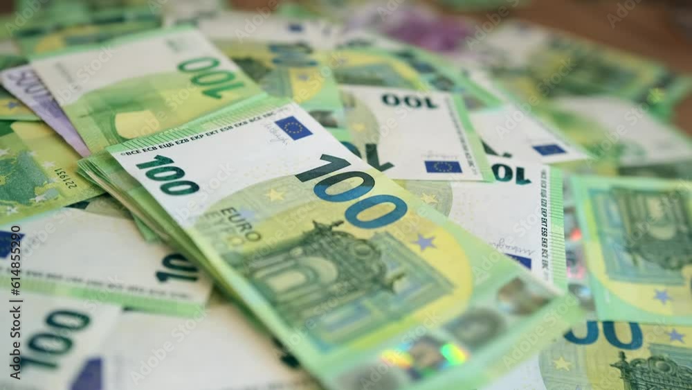 Male hand giving hundred euro banknotes on money background, close up. Pile of euro banknotes lies on table. Financial management and budgeting. Male hand giving hundred euro banknotes on money background, close up. Pile of euro banknotes lies on table. Financial management and budgeting.