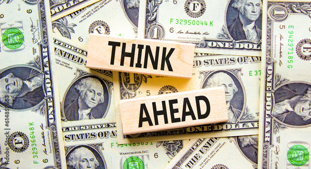 Think ahead symbol. Concept words Think ahead on wooden blocks on a beautiful background from dollar bills. Dollar bills. Business, support, motivation, psychological think ahead concept. Copy space.