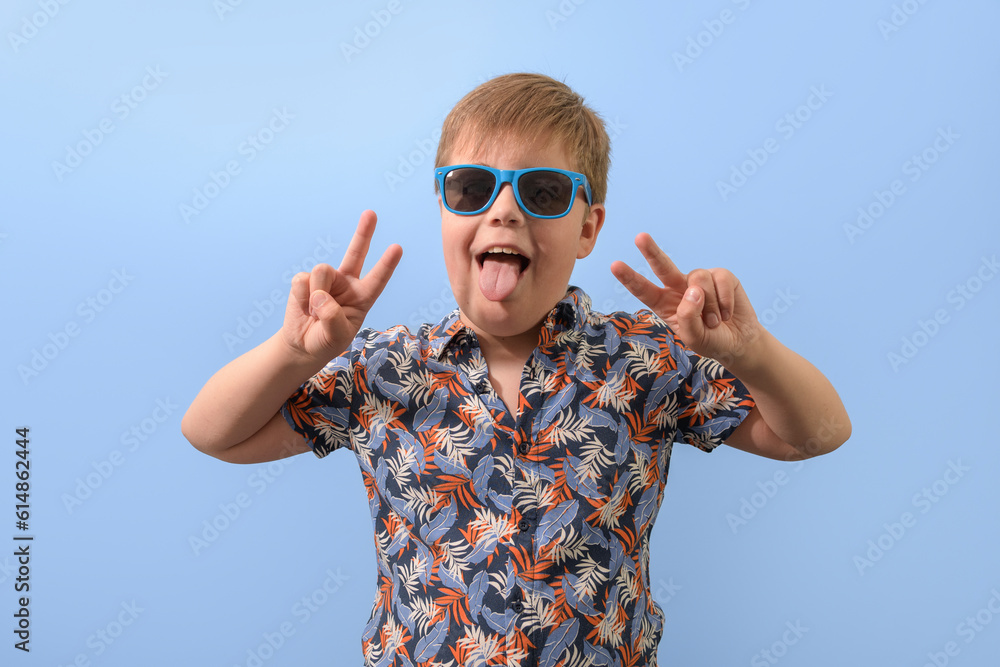 Portrait of a teenage boy in a Hawaiian shirt and blue sunglasses. With raised hands rejoices looking at the camera. Portrait of a teenage boy in a Hawaiian shirt and blue sunglasses. With raised hands rejoices looking at the camera.