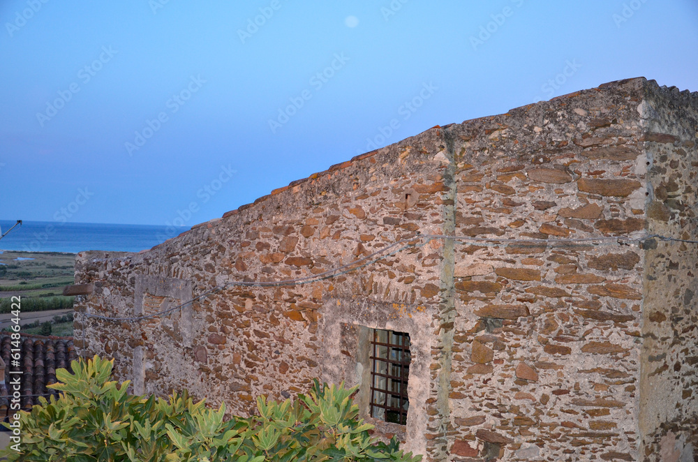 Old stone building in a mountain village in Sardinia with view towards the Mediterranean Sea during dusk