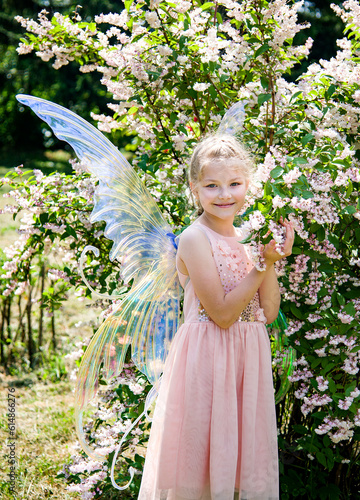 ittle beautiful girl in a fairy costume of butterfly having fun in roses garden on sunny summer day