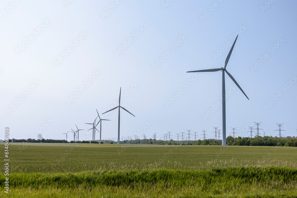 Windmills are lined up in a farmer's field in rural Ontario, outside of Port Elgin on a beautiful sunny day with a clear blue sky. Windmills are lined up in a farmer's field in rural Ontario, outside of Port Elgin on a beautiful sunny day with a clear blue sky.
