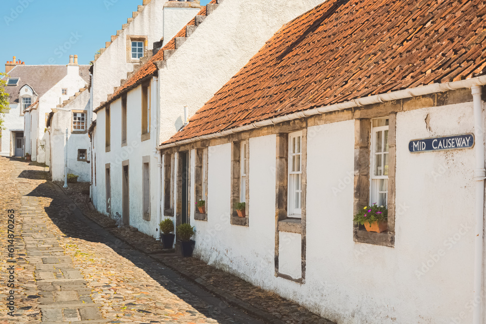 Charming and quaint old town cobblestone lane and white harling cottages in the medieval village of Culross, a popular filming location in Fife, Scotland, UK.