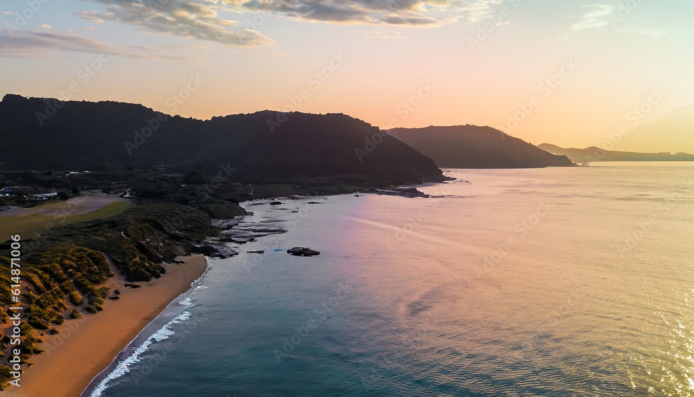 Fototapeta premium aerial beautiful shot of a seashore with hills on the background at sunset