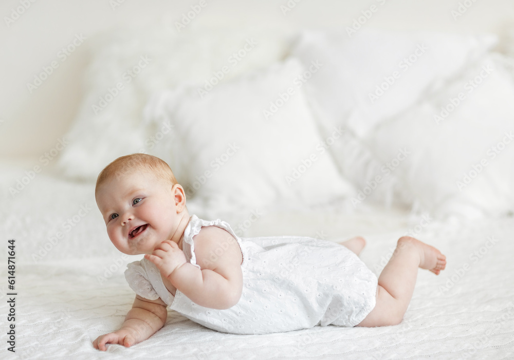 The concept of childcare. Happy little red-haired girl playing on a white blanket in a sunny nursery. Selective focus, free copy space. High quality photo