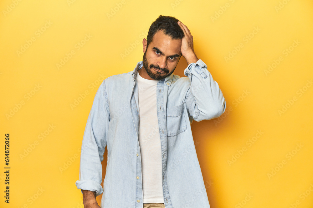 Casual young Latino man against a vibrant yellow studio background, tired and very sleepy keeping hand on head. Casual young Latino man against a vibrant yellow studio background, tired and very sleepy keeping hand on head.